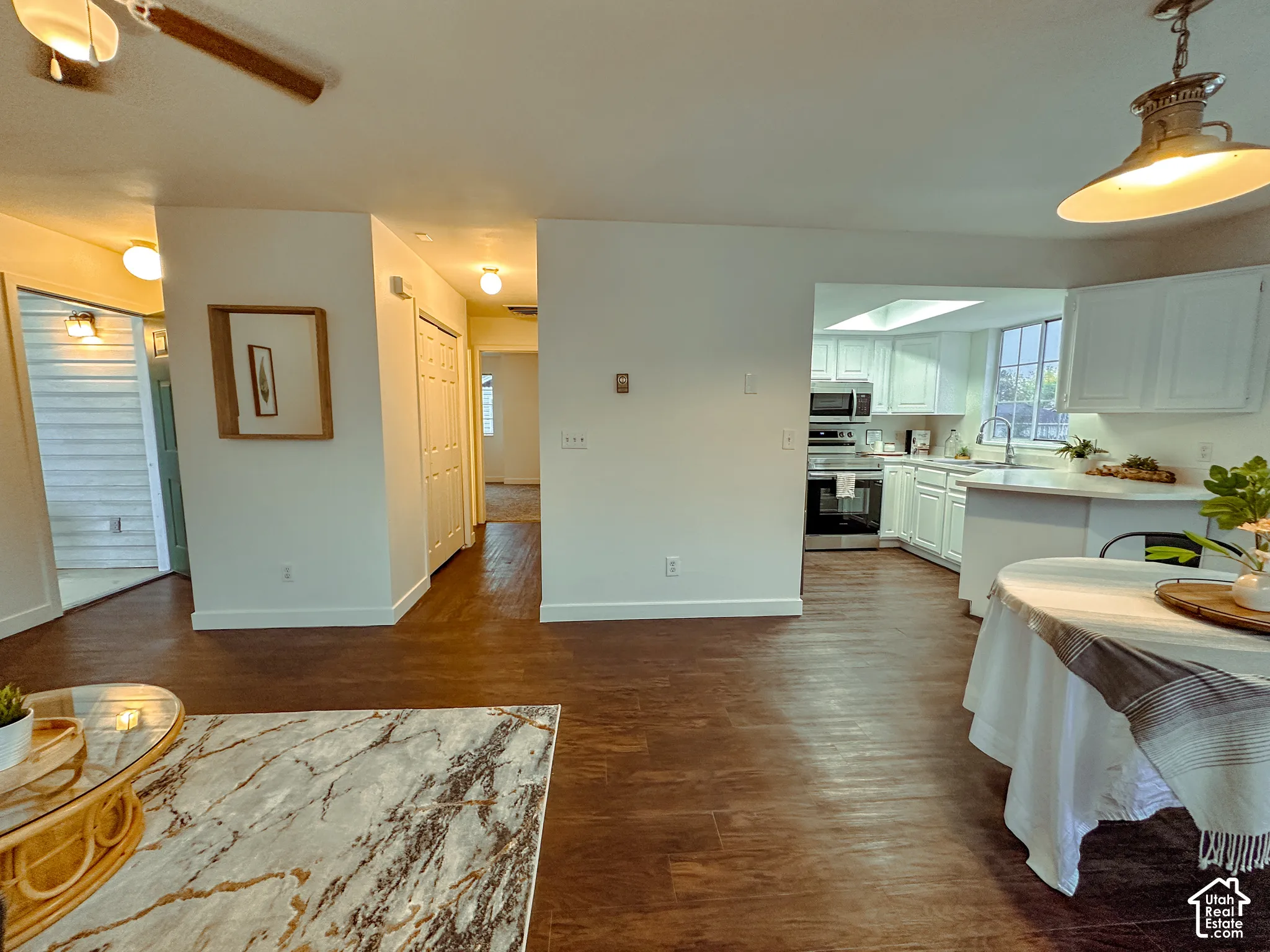 Kitchen featuring white cabinetry, solid-surface countertops, and built-in stainless steel appliances, complemented by dark wood-finish flooring