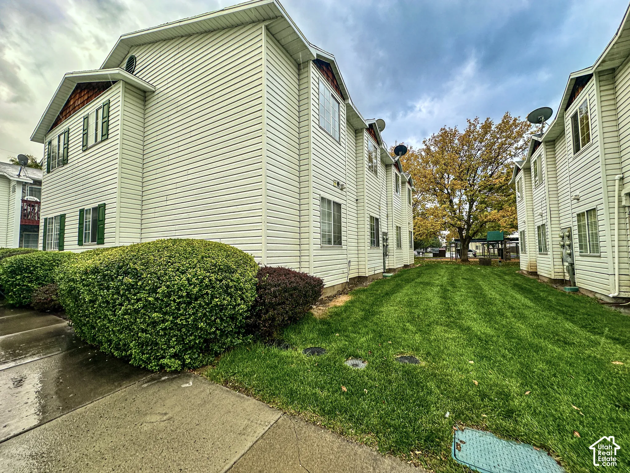 Multi-level exterior featuring horizontal siding, decorative window shutters, and gable rooflines, complemented by a manicured lawn and mature landscaping