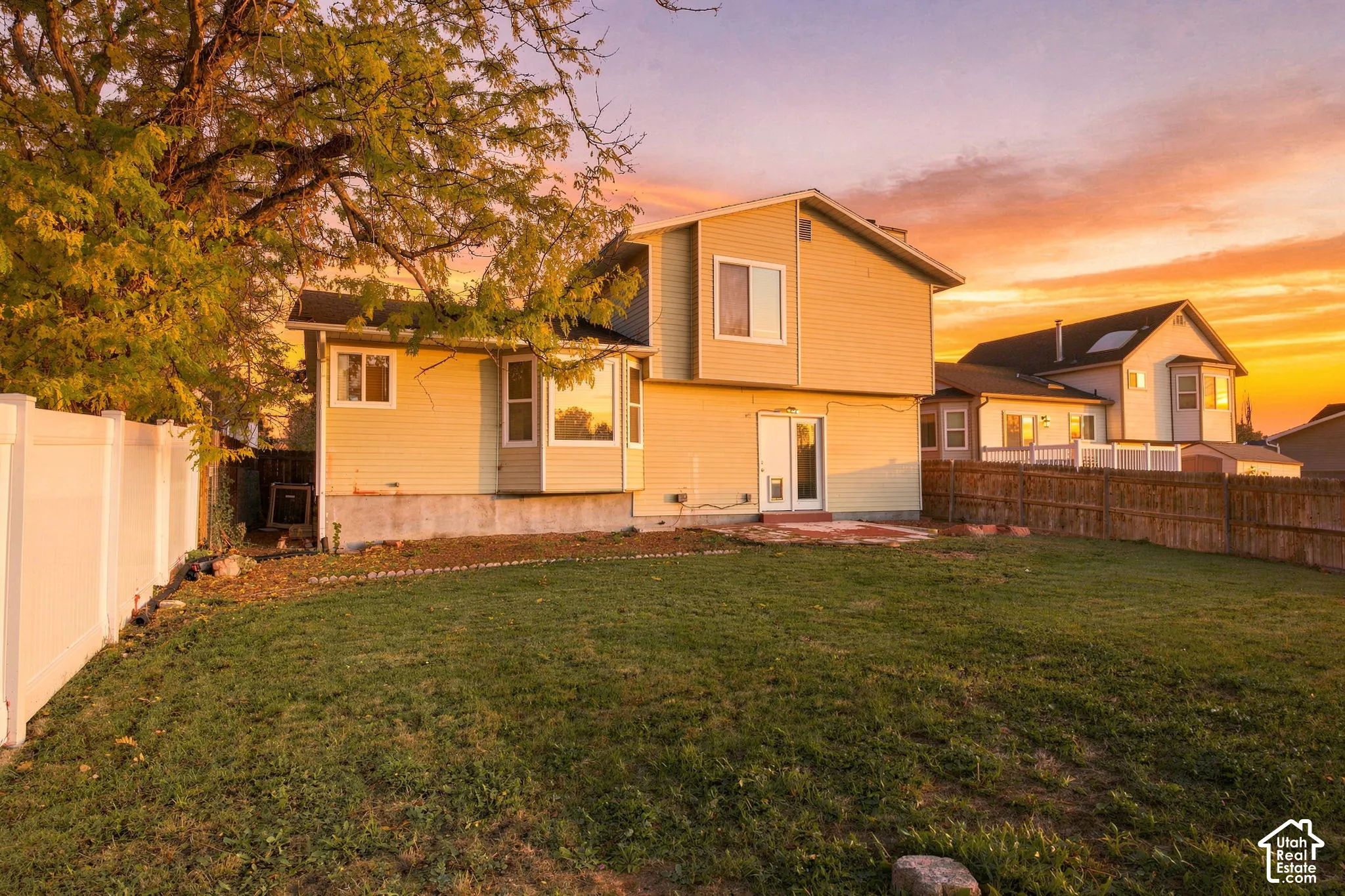 Two-story exterior with horizontal siding, bay windows, rear patio, and enclosed yard with perimeter fencing