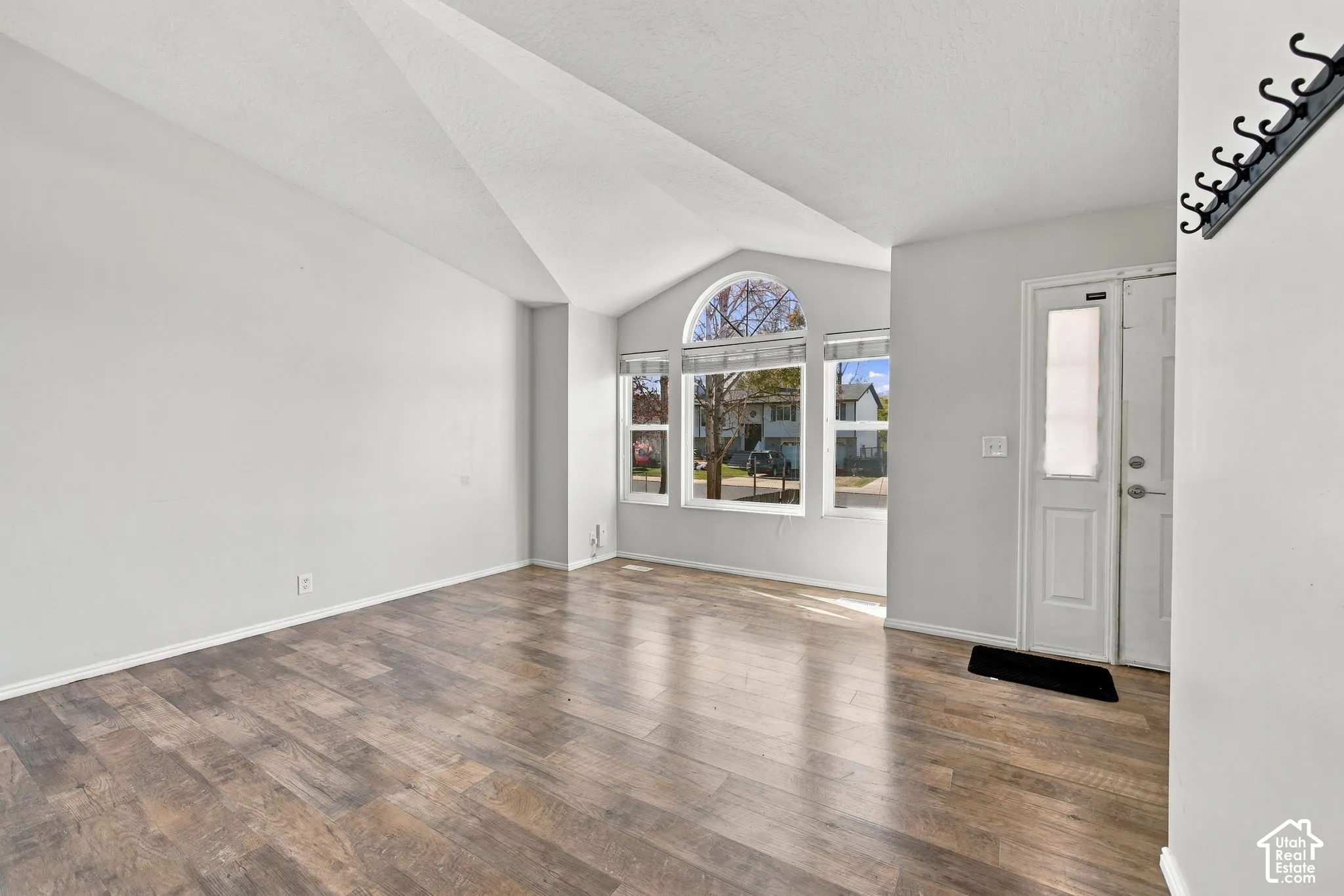 Vaulted ceilings, wood-finish flooring, and an arched window configuration providing natural light