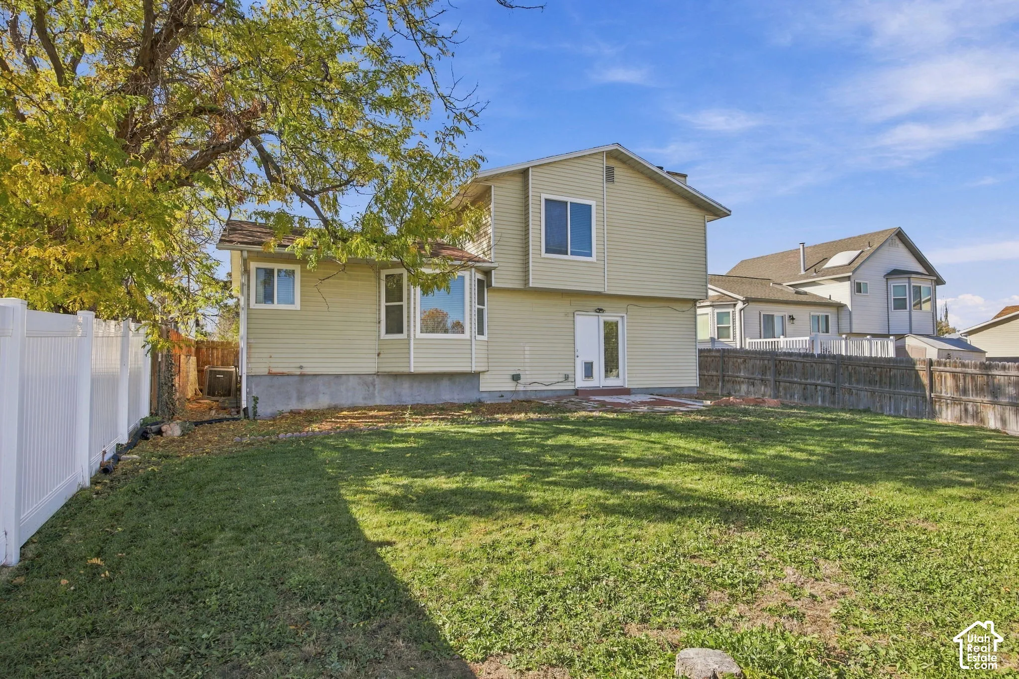 Two-story exterior with light-colored siding, bay windows, white vinyl fencing, and a fenced backyard
