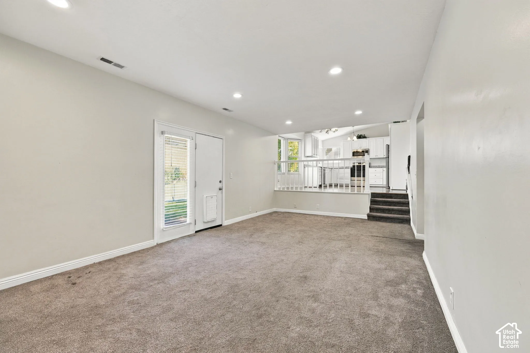 Interior space featuring recessed lighting, carpeting, glass-paned exterior door, elevated platform area, and white railing