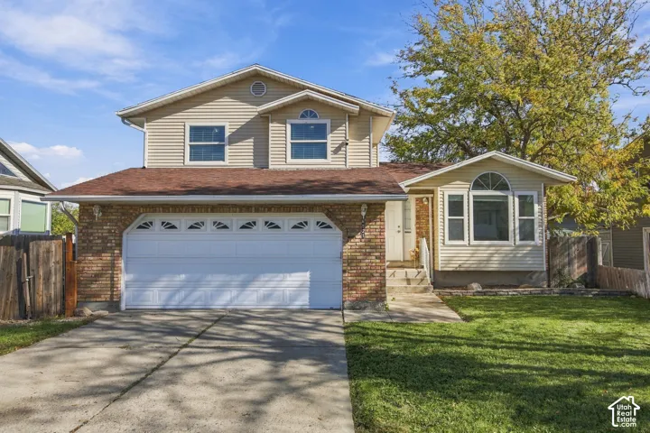 Two-story exterior featuring a brick and horizontal siding facade, an attached two-car garage, an arched window detail, and a concrete driveway
