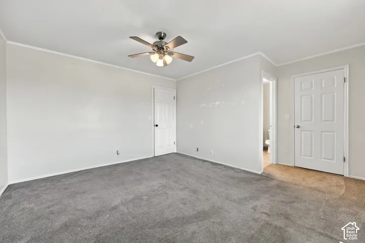 Neutral interior featuring grey carpeting, ceiling fan with integrated lighting, and white paneled doors