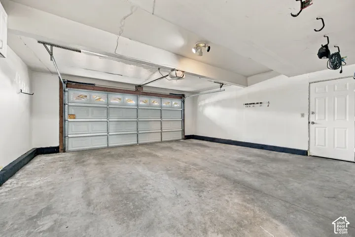 Multi-car garage featuring a sectional overhead door, concrete flooring, dual-bulb ceiling-mounted lighting, and an exterior access door