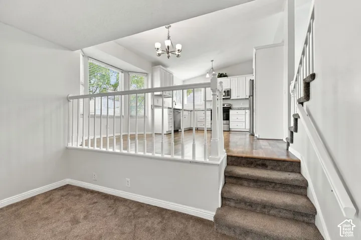 Interior space featuring vaulted ceilings, wood-finish flooring, white cabinetry, bay window, and a white balustrade