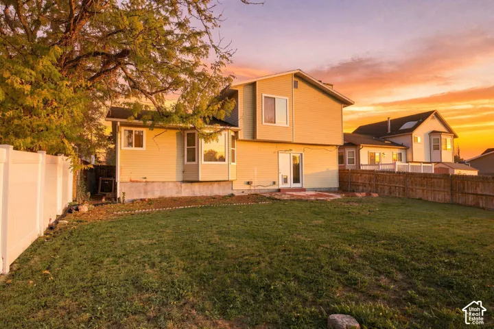 Two-story exterior with horizontal siding, bay windows, rear patio, and enclosed yard with perimeter fencing