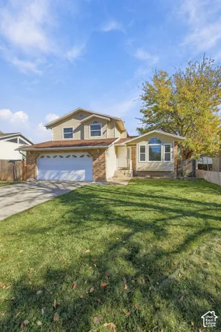 Two-story residence featuring a brick and siding exterior, two-car garage, arched window accents, and a front lawn