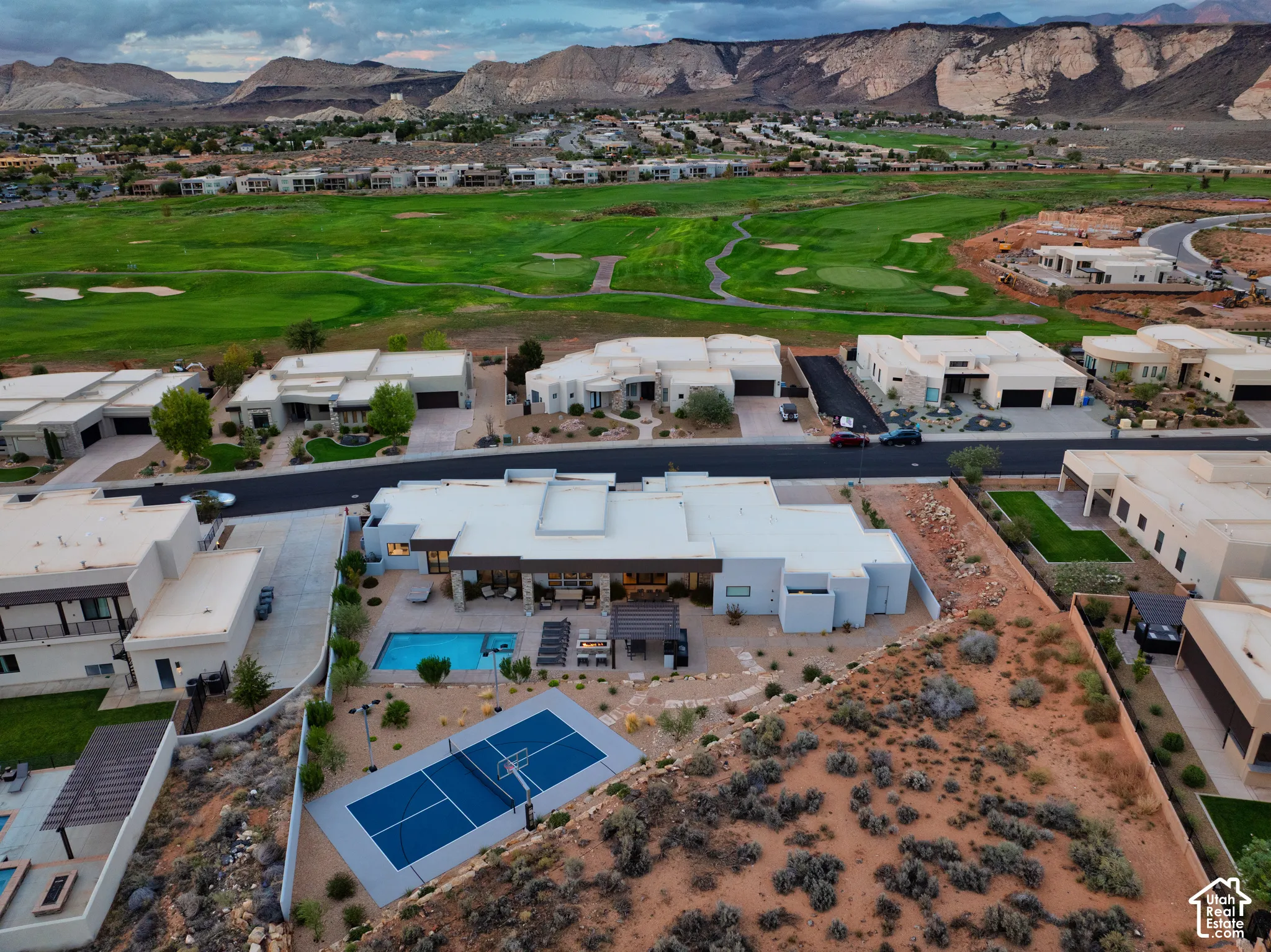 Aerial of the home, pool and lighted sport court, with The Ledges golf course and red rock beyond