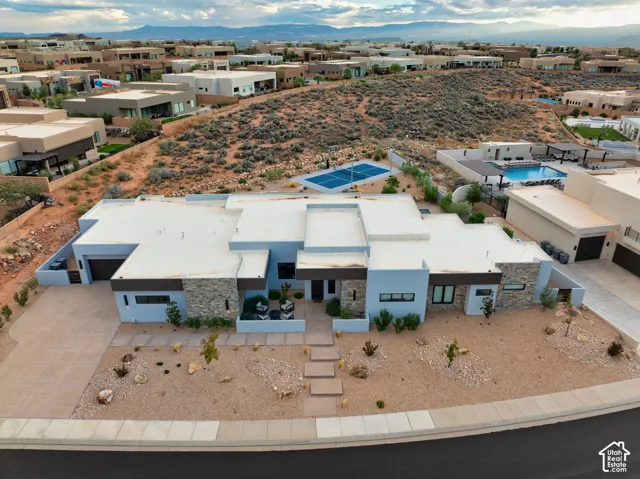 Contemporary residence featuring a multi-level flat roofline, natural stone exterior accents, an integrated multi-car garage, xeriscape landscaping, and a paved walkway