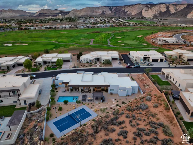Aerial of the home, pool and lighted sport court, with The Ledges golf course and red rock beyond