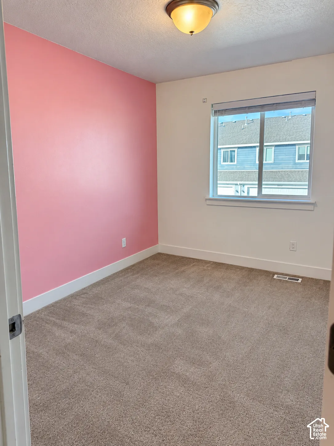 Room featuring neutral-toned carpeting, a single accent wall, a sliding window with integrated blinds, and a semi-flush mount ceiling fixture