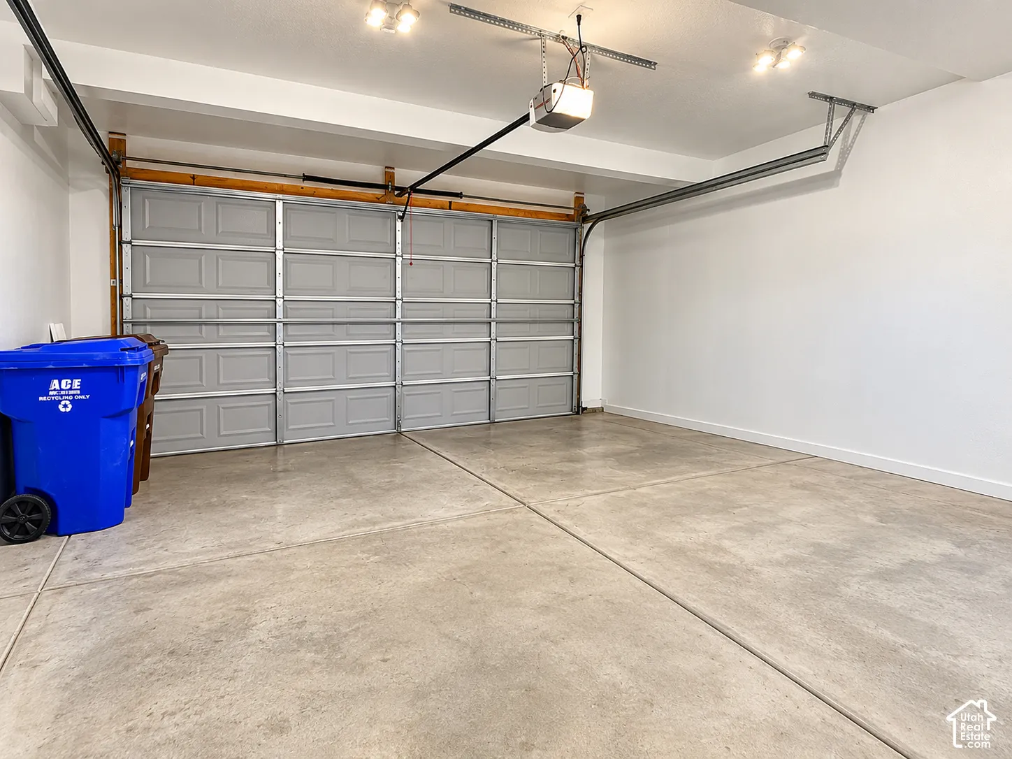 Two-car garage featuring a sectional door, concrete flooring, and ceiling-mounted automatic garage door opener