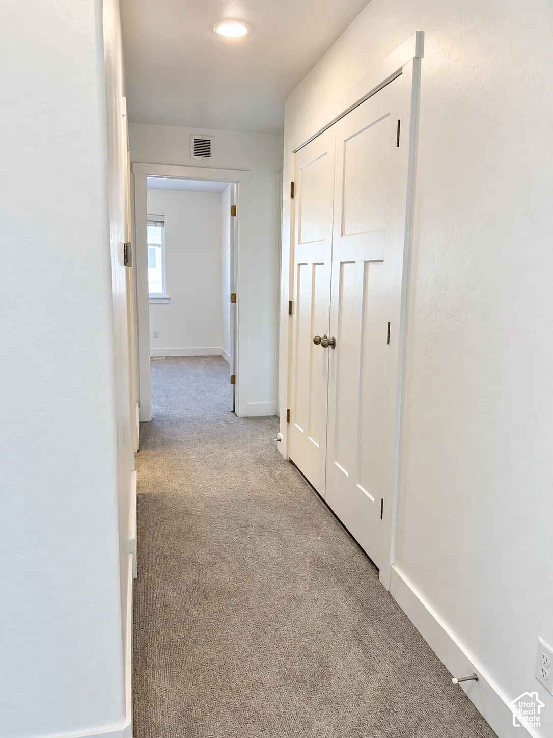 Neutral-toned carpeting, recessed ceiling lighting, and double-panel shaker-style closet doors with metallic hardware
