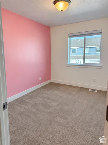 Room featuring neutral-toned carpeting, a single accent wall, a sliding window with integrated blinds, and a semi-flush mount ceiling fixture