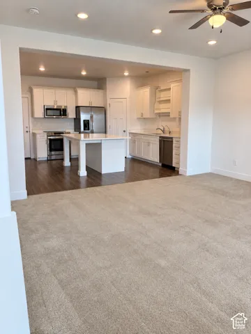 Kitchen featuring white cabinetry, center island with stone countertop, wood-finish flooring, stainless steel appliances, and recessed lighting