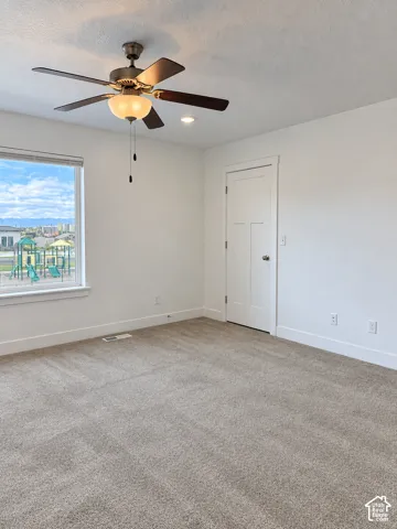 Neutral-toned carpeting, ceiling fan with integrated light fixture, recessed lighting, and a solid-core three-panel interior door