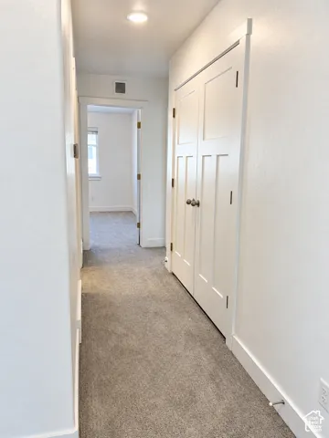 Neutral-toned carpeting, recessed ceiling lighting, and double-panel shaker-style closet doors with metallic hardware