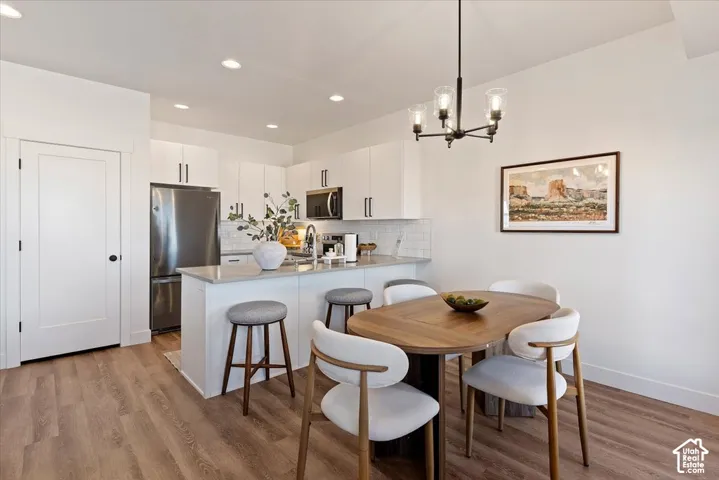 Kitchen featuring white cabinetry with matte black hardware, quartz countertops, stainless steel appliances, recessed lighting, and wood-finish flooring
