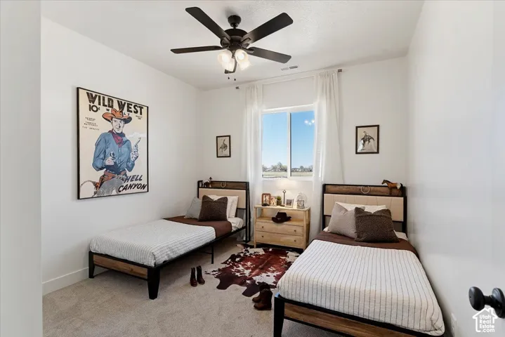 Bedroom featuring neutral carpeting, a central ceiling fan with integrated lighting, and a window providing natural light