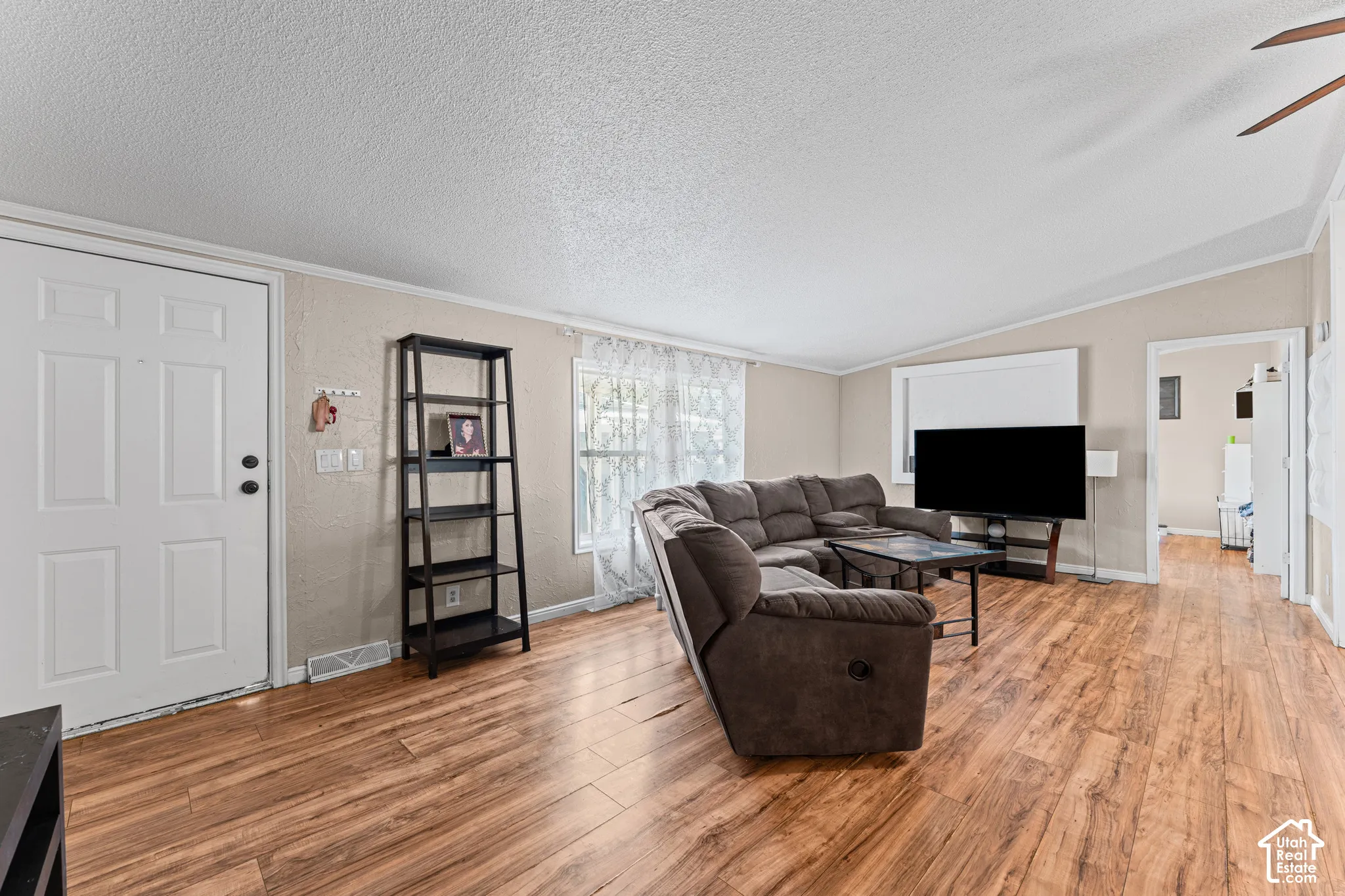 Open-concept living space featuring wood-finish flooring, vaulted ceilings, and natural light from multiple windows