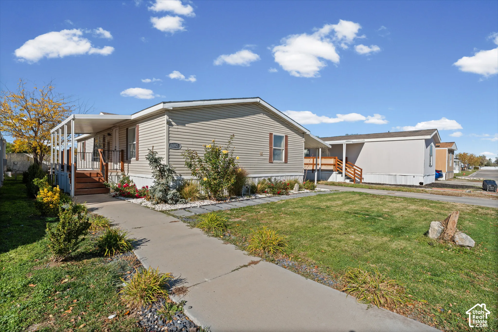 Vinyl siding exterior featuring a covered front porch, concrete walkway, and landscaped garden beds