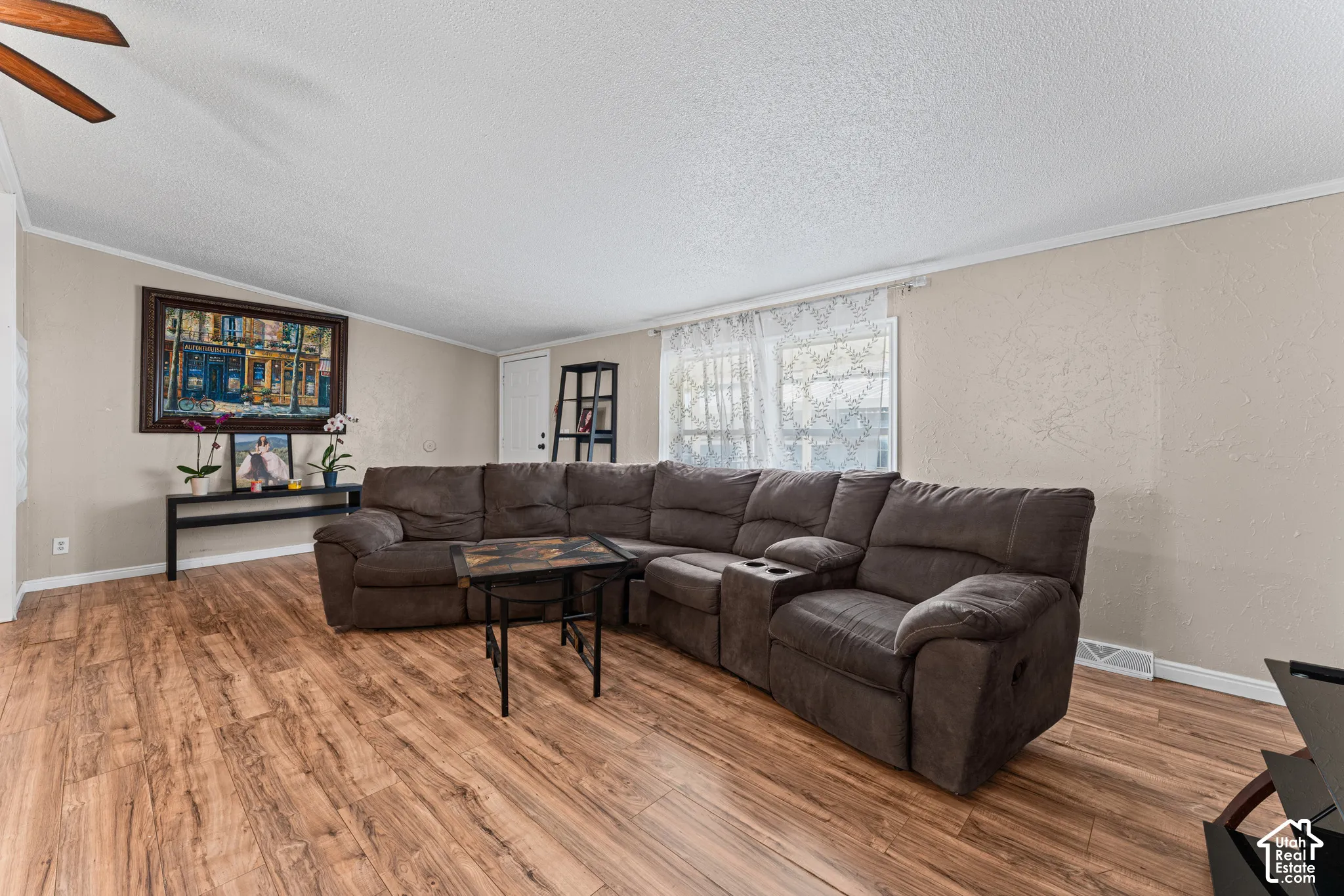 Living area featuring wood-finish flooring, textured ceiling, and a ceiling fan