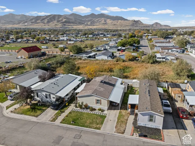 Aerial perspective featuring residential structures with attached metal carports, concrete driveways, and mountain range backdrop