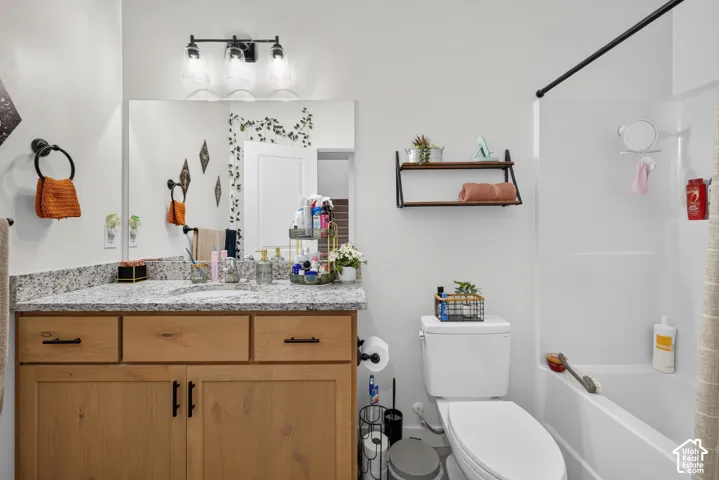 Bathroom vanity featuring natural wood-finish cabinetry, stone-composite countertop with an integrated basin, matte black hardware, and a three-light wall-mounted fixture