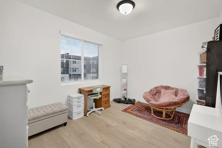 Room with wood-finish flooring, white walls, flush-mount ceiling lighting, and a window with horizontal blinds