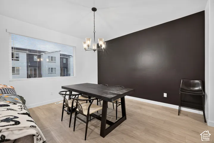 Interior space featuring a dark-toned accent wall, wood-finish flooring, and a multi-light metal chandelier