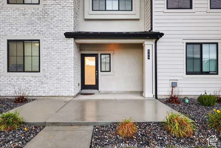 Exterior facade featuring a combination of white brick and horizontal siding, a covered concrete porch, and black window frames