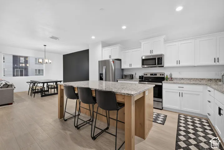 Kitchen featuring white cabinetry, stone-surface countertops, wood-finish island base, stainless steel appliances, and recessed lighting