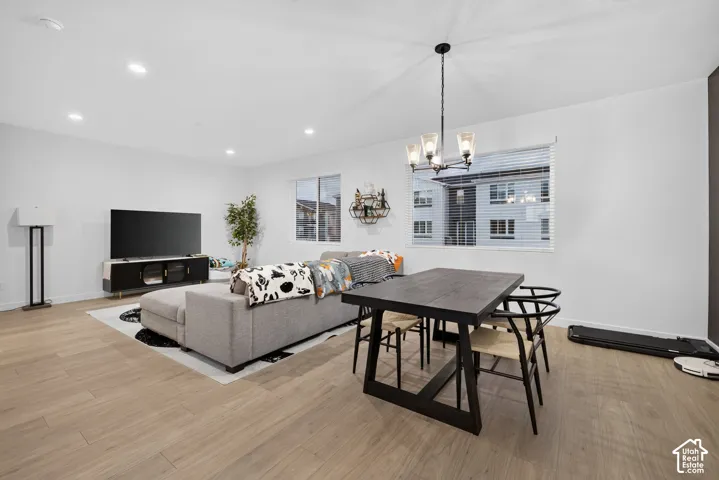 Open-concept interior featuring light wood-finish flooring, recessed lighting, and a multi-arm metal chandelier