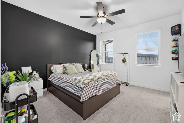 Room featuring a high-contrast black accent wall, neutral carpeting, and a central ceiling fan with integrated lighting