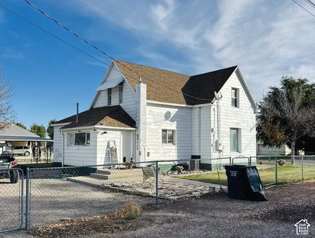 Two-story residence featuring white horizontal siding, an exterior chimney, a composite shingle roof, and a concrete patio