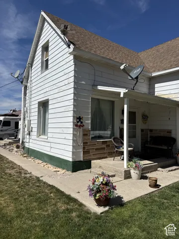 Exterior featuring white lap siding, stone veneer accents, an asphalt shingle roof, and a concrete front porch