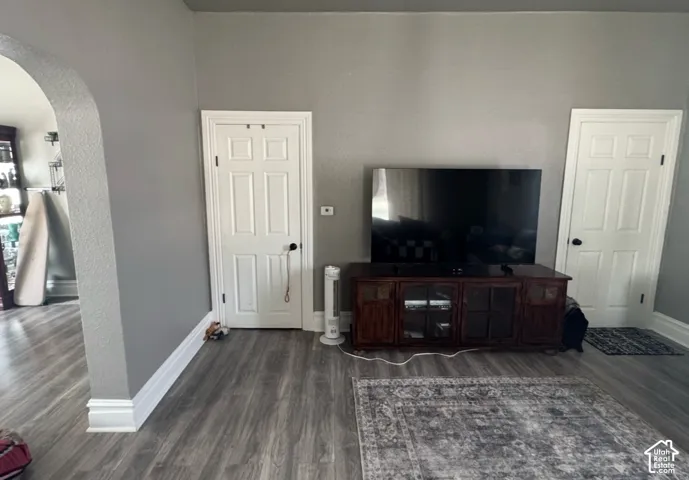 Arched entryway featuring neutral-toned walls, wood-finish flooring, and white six-panel interior doors