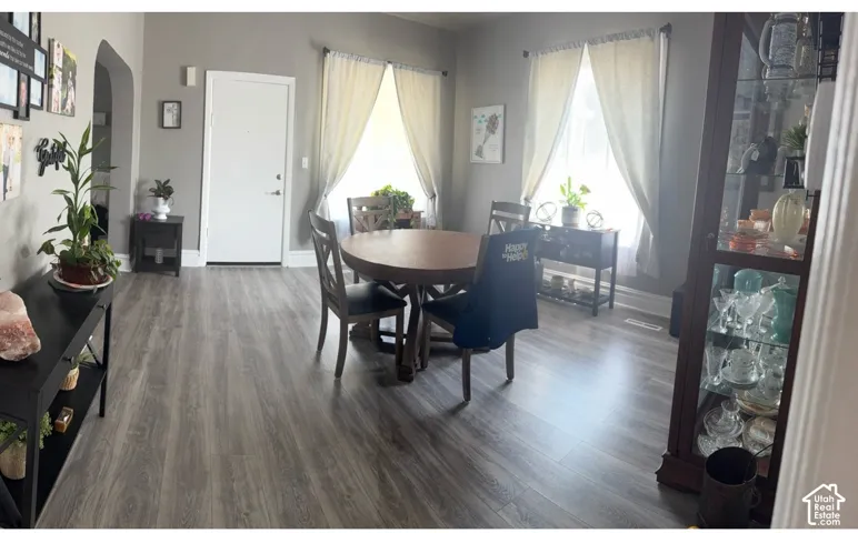 Neutral-toned interior space featuring wood-finish flooring, two windows with natural light, and an arched doorway