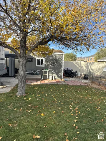 Outdoor space featuring a storage shed, red paver patio area, concrete carport, and perimeter privacy fencing