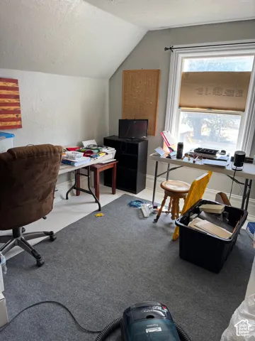 Room featuring sloped ceilings, carpeted flooring, and a window with white trim