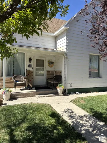 Exterior featuring horizontal siding, a covered porch with stone masonry accents, and a concrete walkway