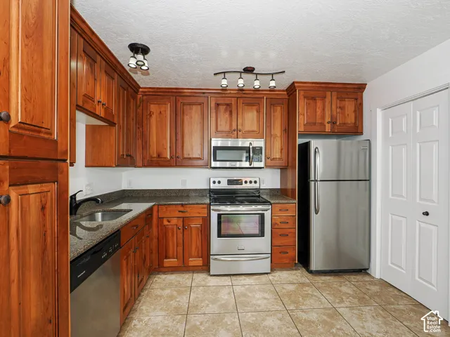Granite countertops with undermount sink, knotty alder raised-panel cabinetry, and stainless steel range with ceramic tile flooring