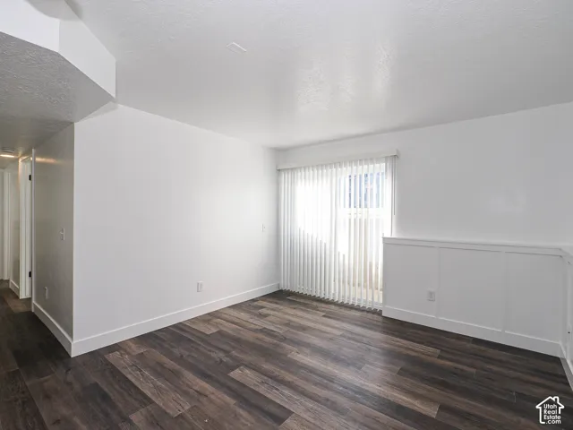 Sun-filled living room in ground-floor unit featuring new LVP flooring, board-and-batten wainscoting, and sliding door to private patio