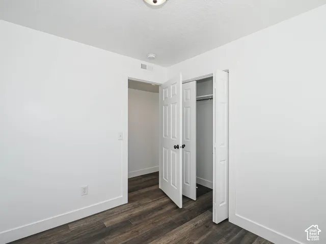 Room featuring wood-finish flooring, white walls, and a closet with six-panel bi-fold doors and matte black hardware