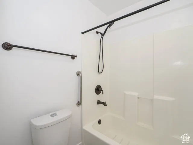 Bathroom featuring a white integrated tub and shower surround, bronze-finish hardware, handheld showerhead, and matching bronze-finish towel bar