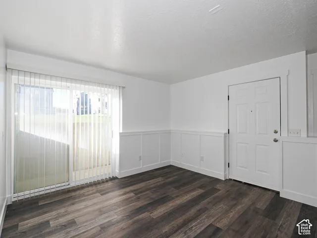 Ground-floor living room featuring new luxury vinyl plank flooring, board-and-batten wainscoting, sliding glass door to private patio, and vertical blinds