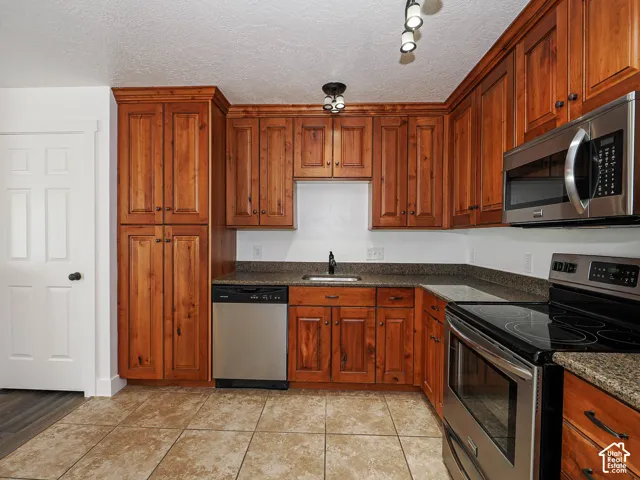 Stainless steel appliances include dishwasher, range, and over-range microwave with full-height pantry cabinetry and granite countertops