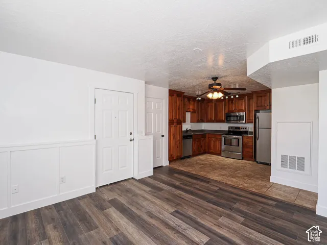 Open flow from kitchen to living area featuring knotty alder cabinetry, stainless appliances, and ceramic tile flooring