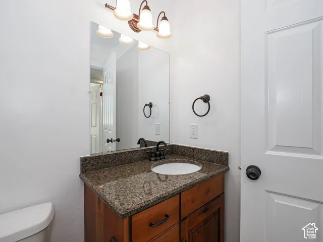 Second bathroom featuring granite countertop vanity, knotty alder cabinetry, large wall mirror, and oil-rubbed bronze fixtures and hardware